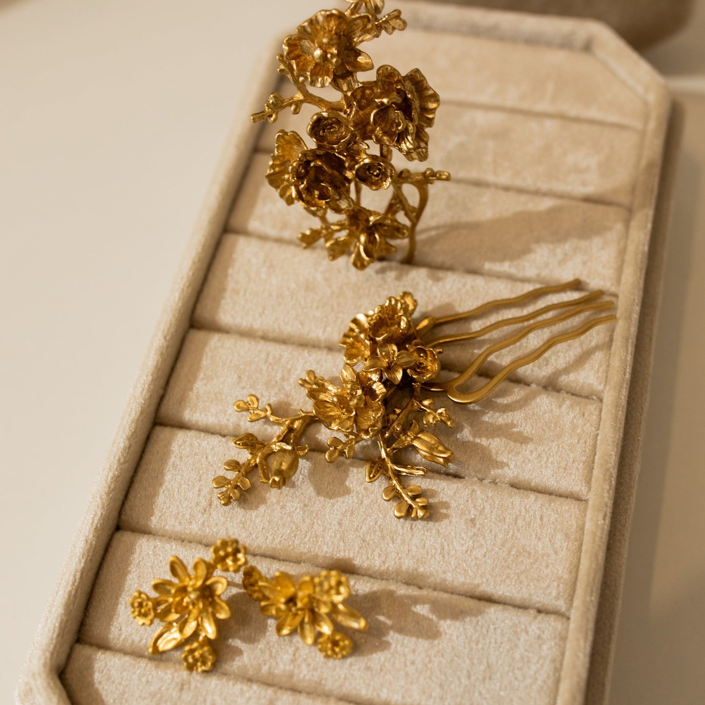 Gold floral hair accessories on a beige jewelry tray