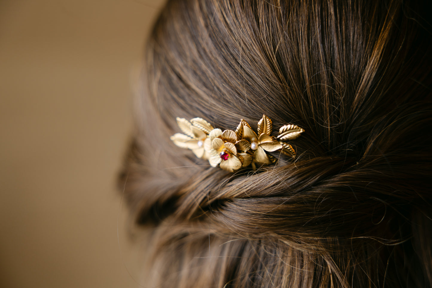Close-up of a decorative headpiece with flowers in brown hair against a beige background