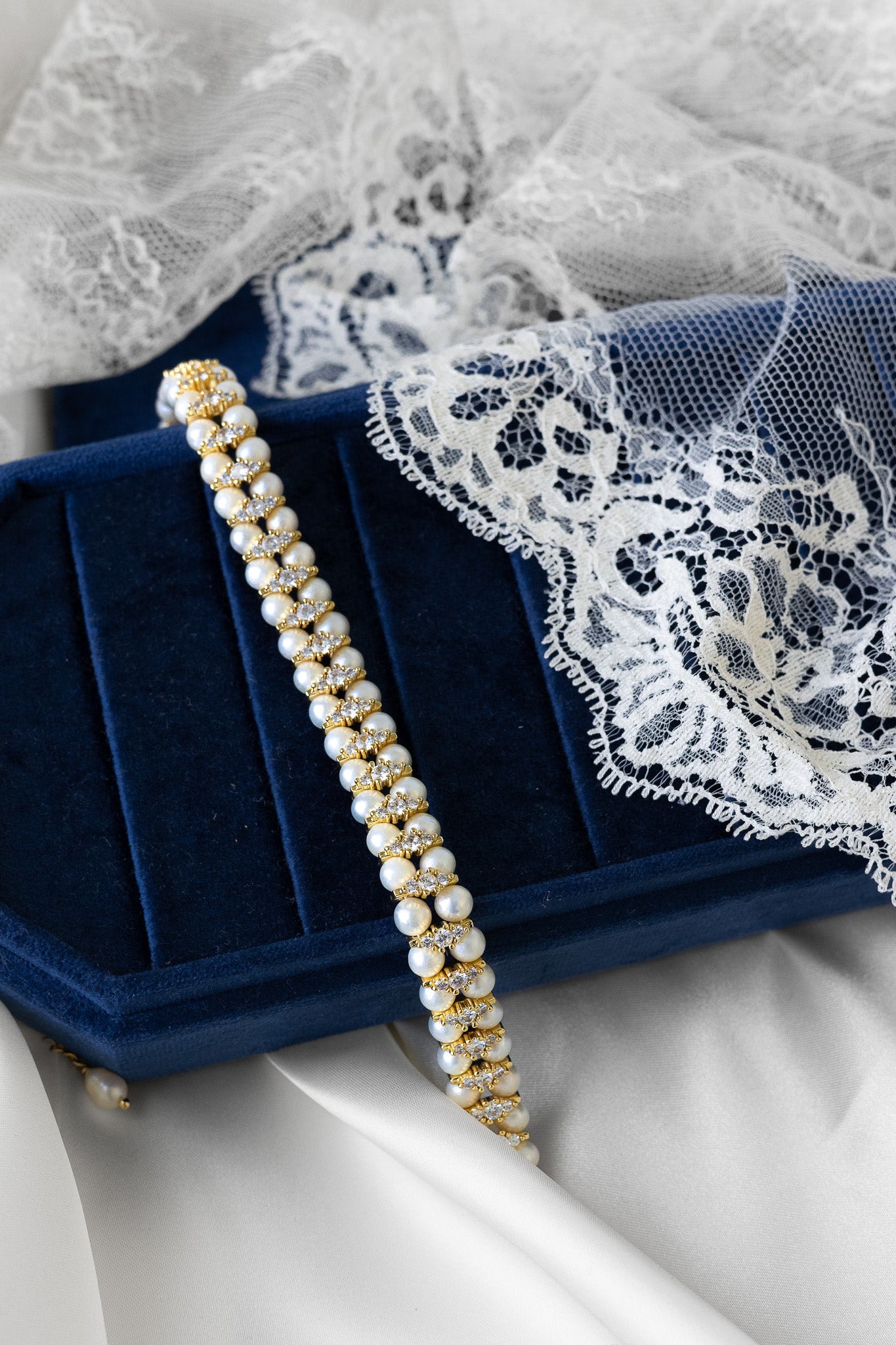 Pearl necklace on a blue velvet box with lace fabric