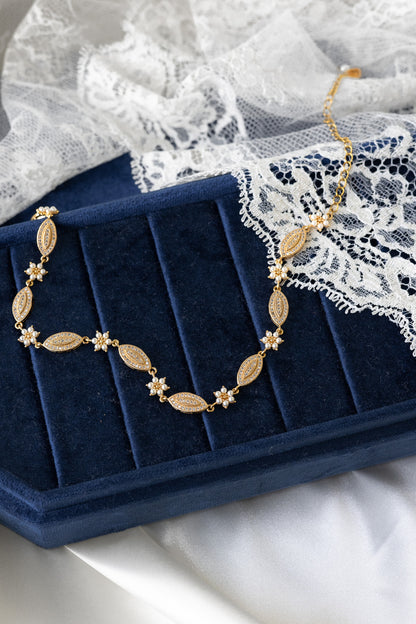 Gold necklace on a blue jewelry box with lace fabric in the background