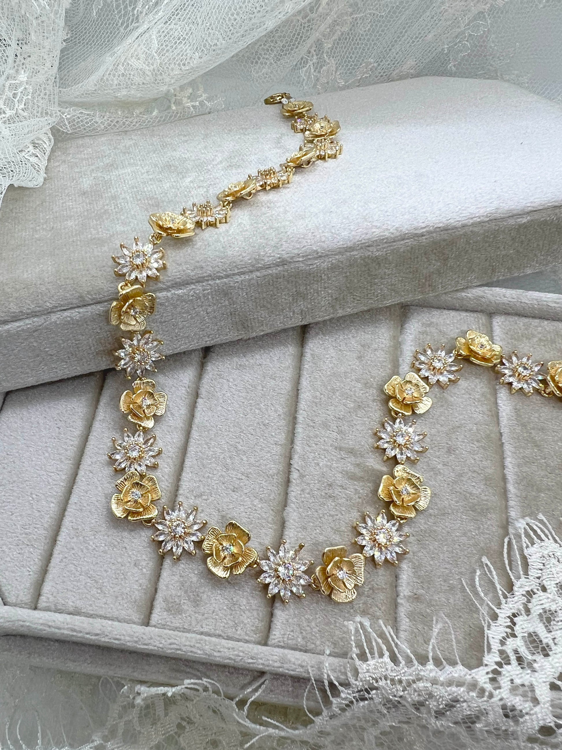 Gold floral necklace on a beige cushion with lace veil