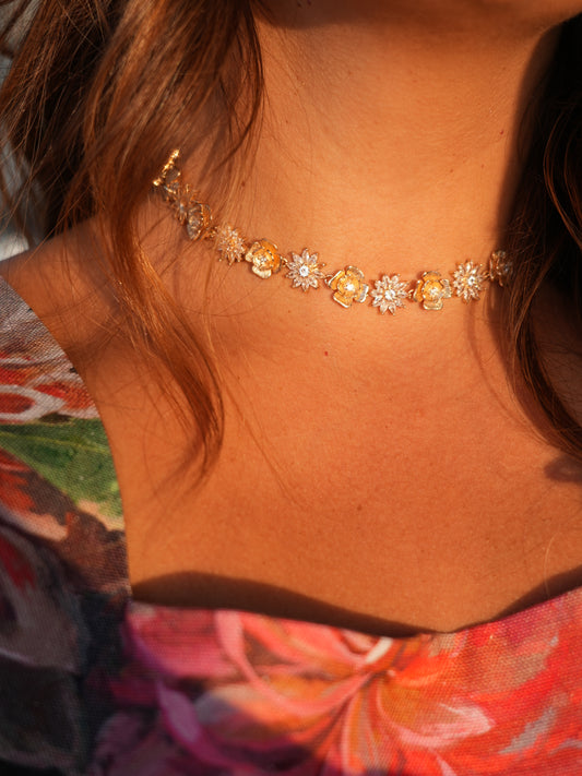 Close-up of a floral choker on a person with a colorful garment in the background