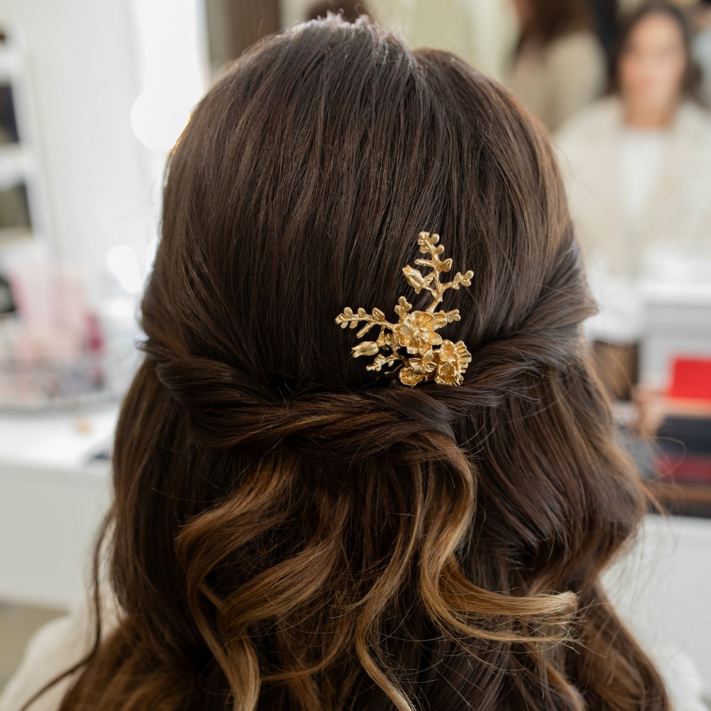 Close-up of wavy hair with a gold hair accessory, blurred background