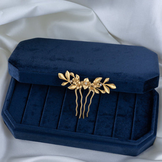 Navy blue clutch with gold floral headpiece on a white fabric background