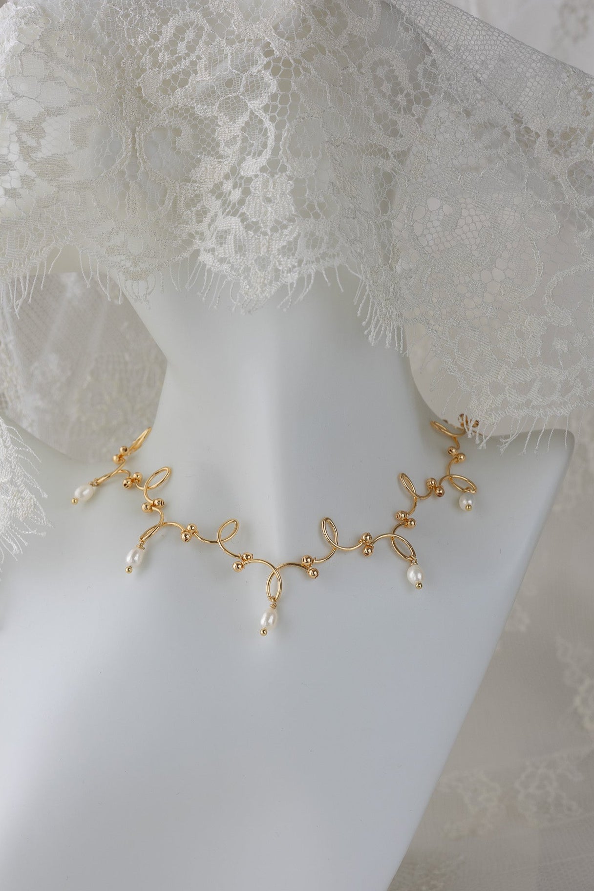 Gold necklace with pearls on a mannequin with lace veil