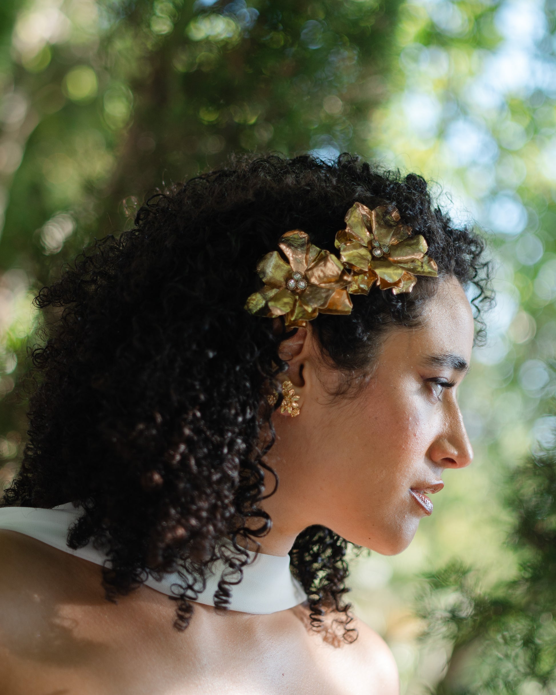 Woman with a gold floral headband against a blurred natural background