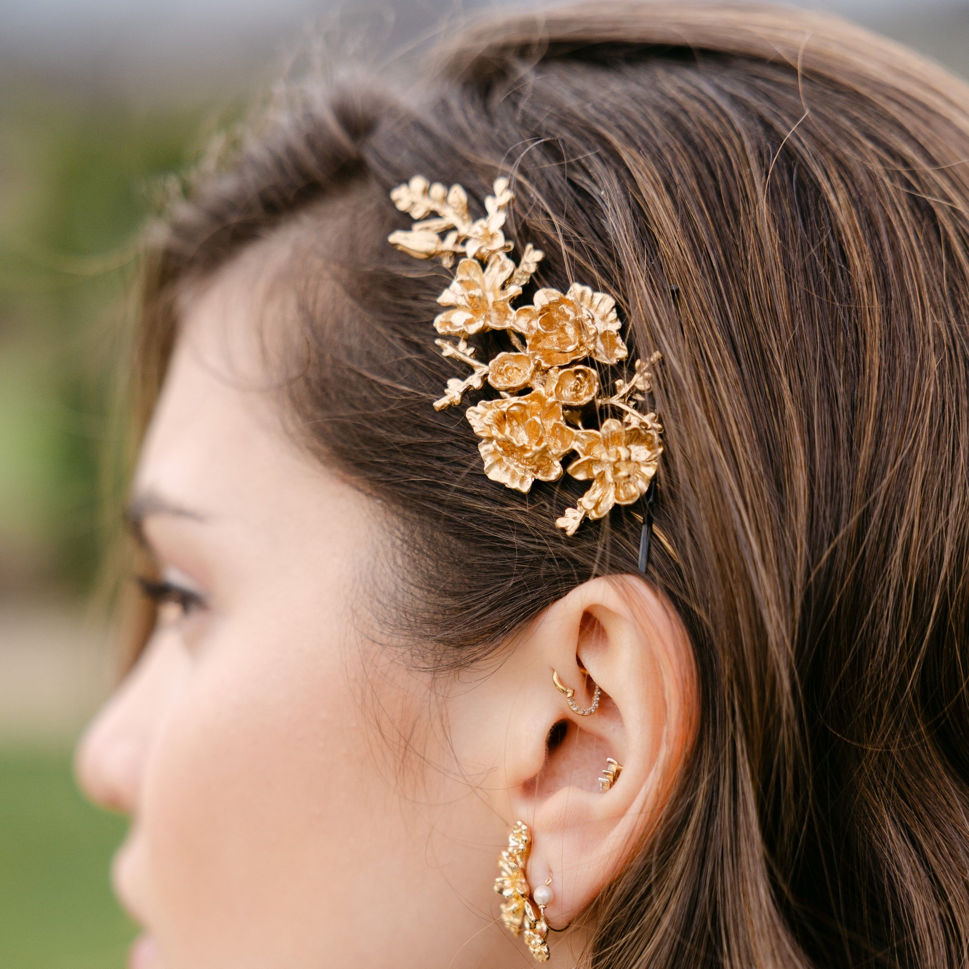 Woman wearing gold floral hairpiece and earrings outdoors