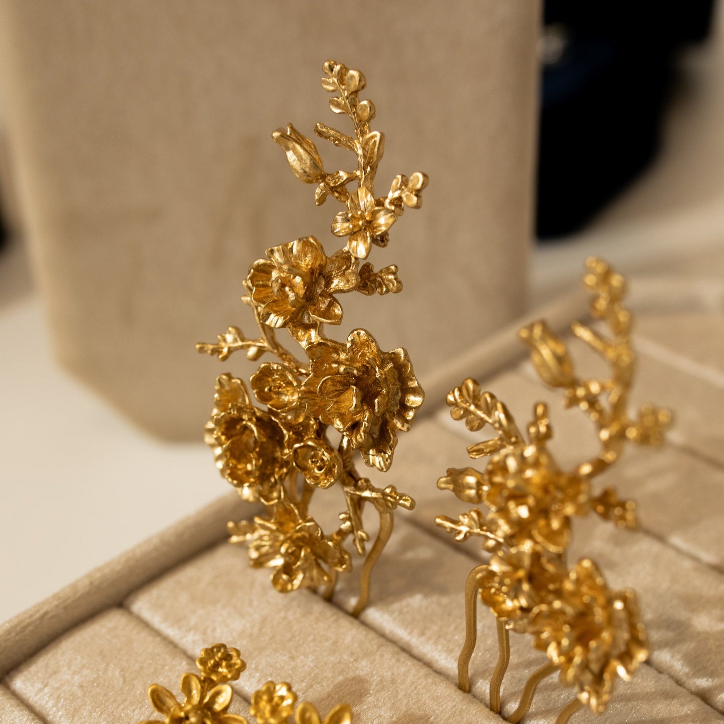 Gold floral earrings on a beige jewelry box