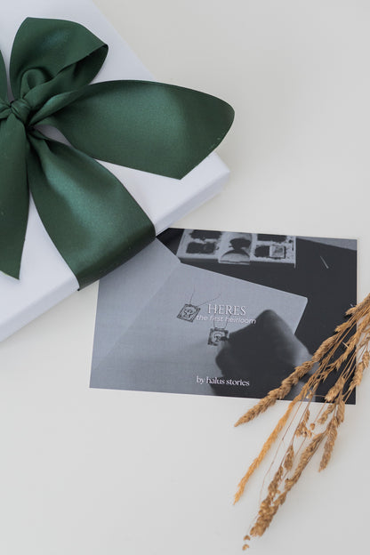 Gift box with a green ribbon and card on a white surface
